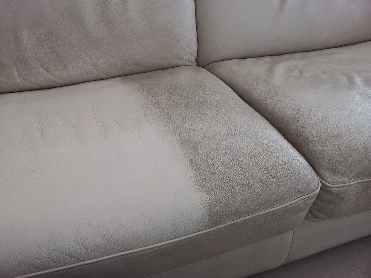 Close de um sofá de couro durante o atendimento: o lado já higienizado, claro e uniforme, ao lado da parte ainda encardida